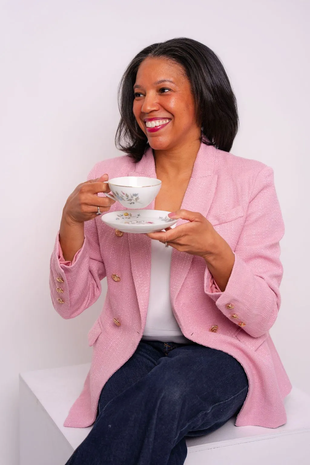 Cecelia smiling in a light pink jacket while holding her grandmother Ada’s floral teacup and saucer